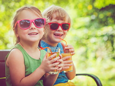 Two young girls wearing sunglasses and tank tops smiling for the camera